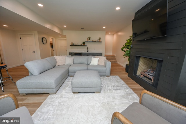 living room with light wood-type flooring, recessed lighting, baseboards, and stairway