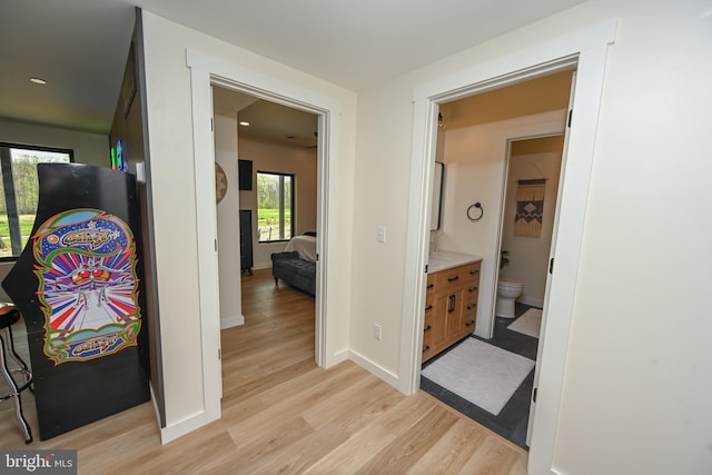 hall with light wood-style flooring, baseboards, and recessed lighting