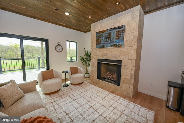 living area with wood ceiling, wood finished floors, baseboards, a large fireplace, and recessed lighting