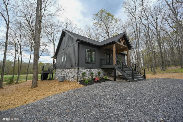 view of front of home featuring board and batten siding, stairway, a porch, central AC, and roof with shingles
