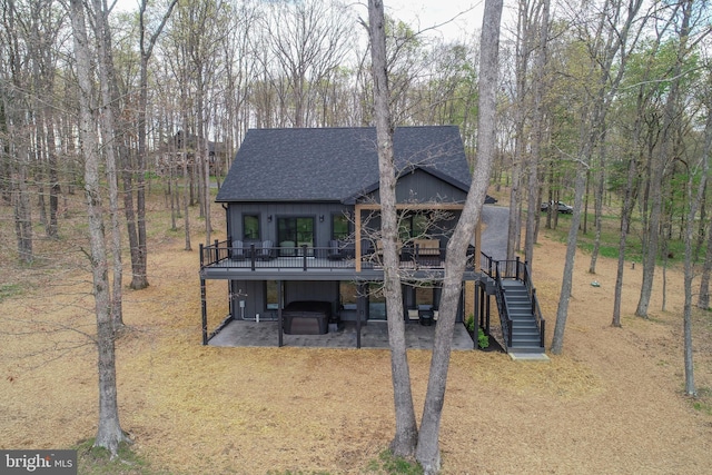 back of house featuring a shingled roof, a patio, stairway, a wooden deck, and board and batten siding