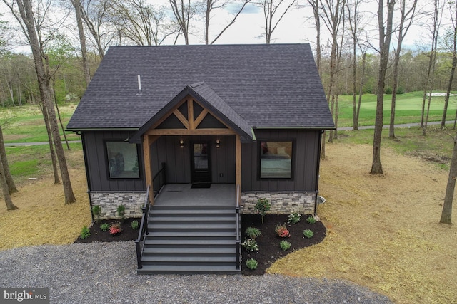 view of front of home with board and batten siding, stone siding, roof with shingles, and a porch