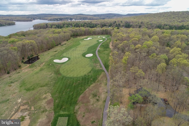 view of property location with a large body of water, a local golf course, and a forest
