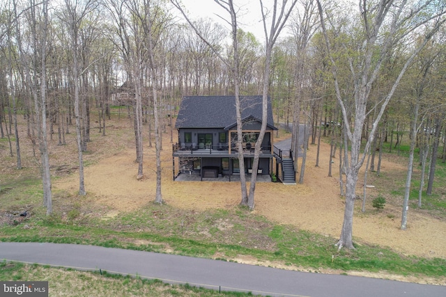 view of front of house with a deck, stairway, and roof with shingles