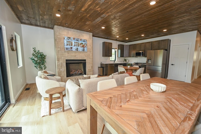 dining area featuring wooden ceiling, light wood-type flooring, a fireplace, baseboards, and recessed lighting