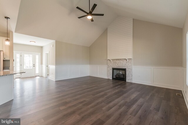 unfurnished living room with a brick fireplace, dark hardwood / wood-style flooring, high vaulted ceiling, and ceiling fan