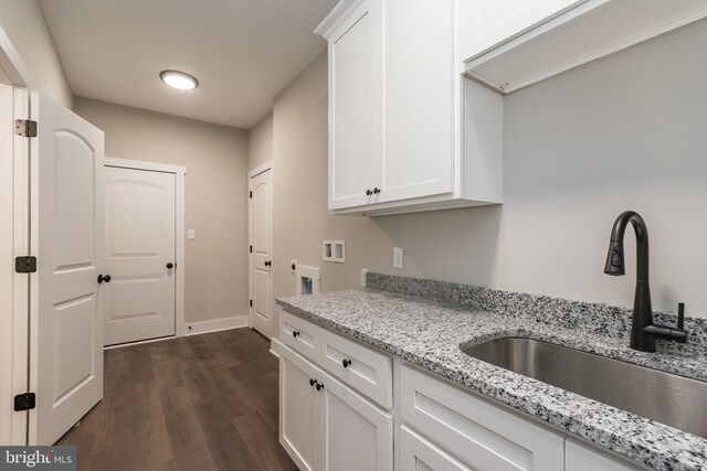 kitchen with white cabinets, dark hardwood / wood-style floors, light stone counters, and sink