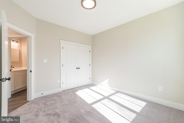 unfurnished bedroom with light colored carpet, connected bathroom, and a closet