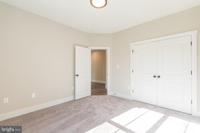 unfurnished bedroom with light carpet and a closet