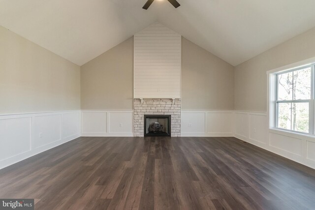 unfurnished living room with ceiling fan, dark wood-type flooring, lofted ceiling, and a brick fireplace