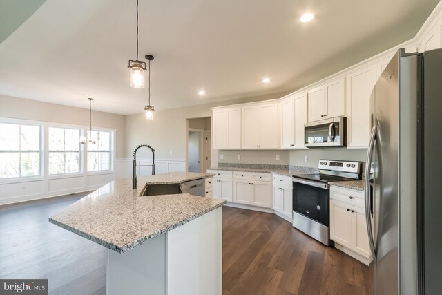 kitchen with dark wood-type flooring, pendant lighting, a kitchen island with sink, white cabinets, and appliances with stainless steel finishes