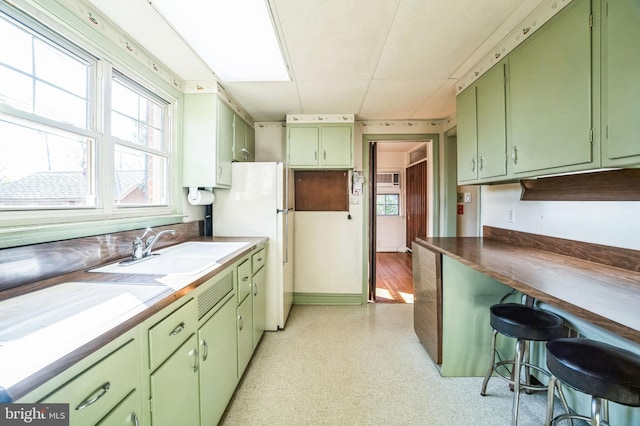 kitchen with green cabinets, sink, and white refrigerator