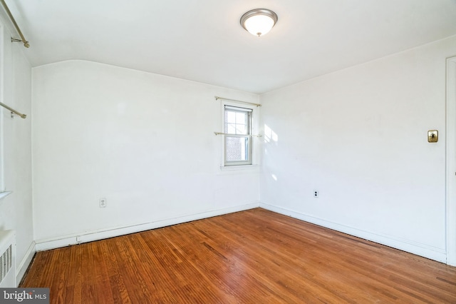 spare room featuring lofted ceiling and hardwood / wood-style flooring