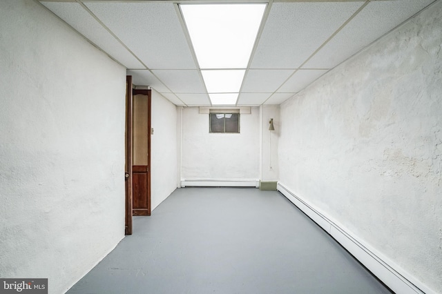 basement featuring baseboard heating and a drop ceiling