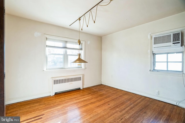 unfurnished dining area featuring light hardwood / wood-style floors, a healthy amount of sunlight, radiator heating unit, and a wall unit AC