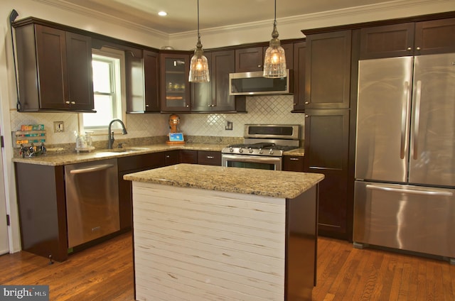 kitchen with sink, stainless steel appliances, light stone counters, dark hardwood / wood-style flooring, and pendant lighting