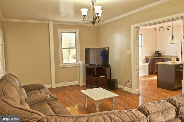 living room featuring hardwood / wood-style flooring, a notable chandelier, and crown molding