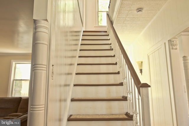 stairs with a wealth of natural light and ornamental molding