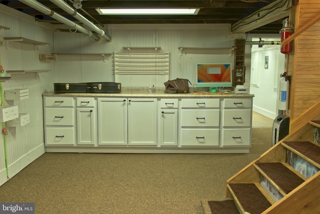 basement featuring dark carpet and wooden walls