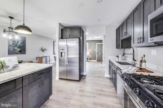 kitchen featuring decorative light fixtures, stainless steel appliances, light hardwood / wood-style floors, and sink