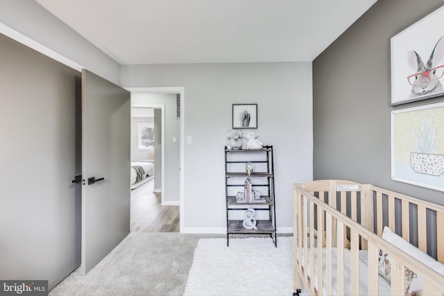 bedroom with light wood-type flooring and a nursery area