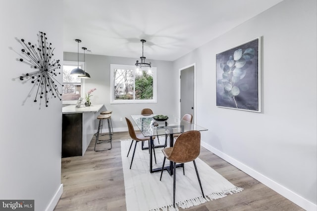 dining space with an inviting chandelier and light hardwood / wood-style flooring