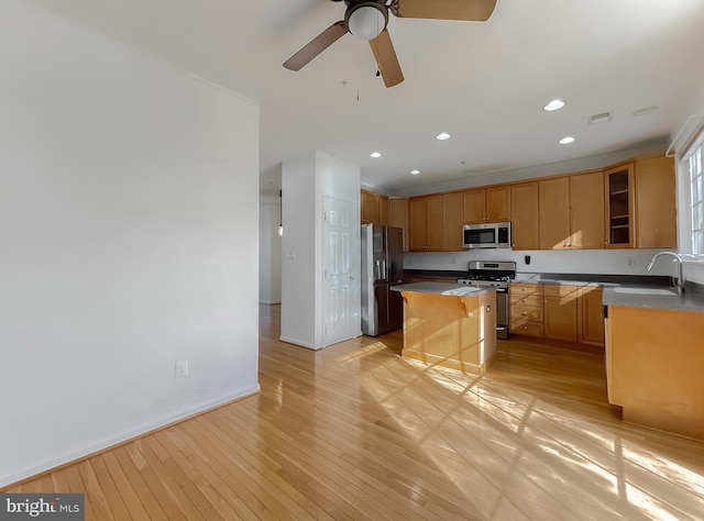 kitchen featuring a center island, sink, stainless steel appliances, a kitchen breakfast bar, and light hardwood / wood-style flooring