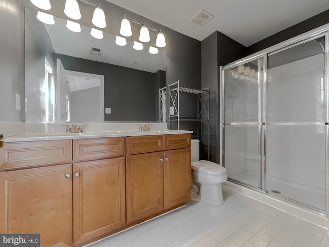 bathroom featuring tile patterned flooring, a shower with door, vanity, and toilet