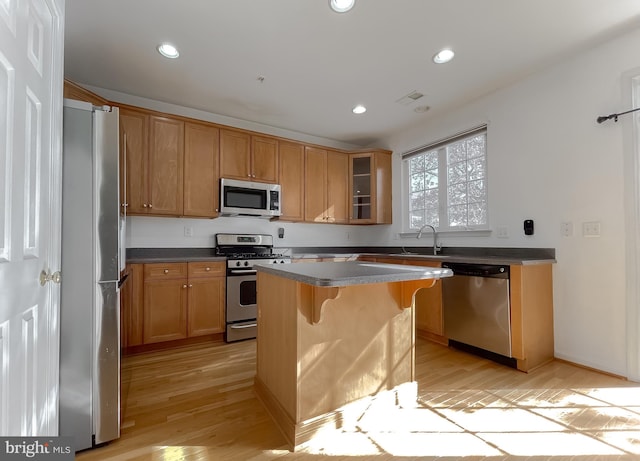 kitchen featuring a kitchen bar, stainless steel appliances, sink, light hardwood / wood-style flooring, and a center island