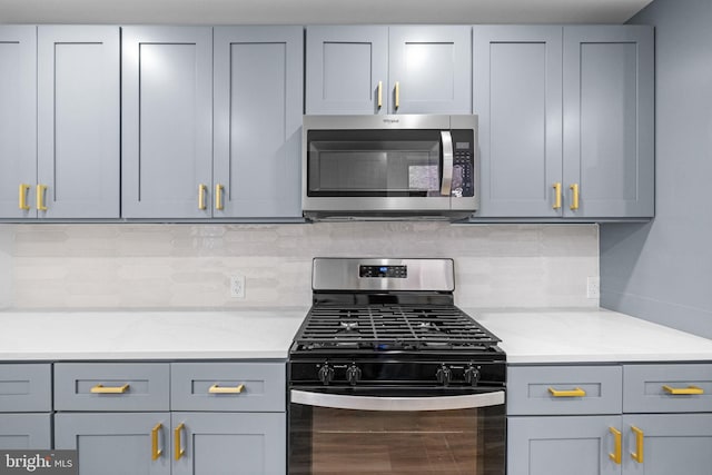 kitchen with gray cabinets, light stone counters, and appliances with stainless steel finishes