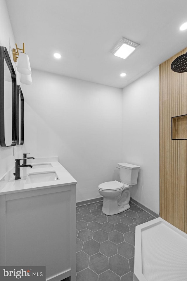 bathroom featuring tile patterned flooring, vanity, toilet, and walk in shower