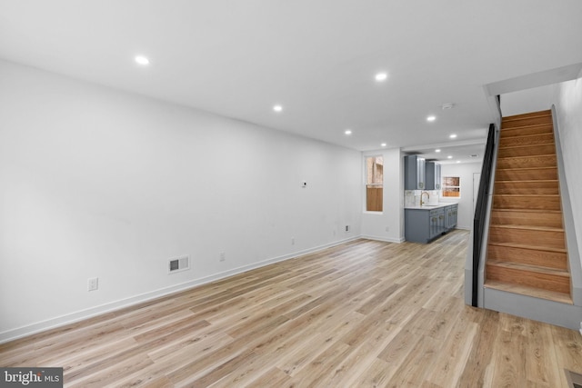 unfurnished living room with sink and light hardwood / wood-style floors