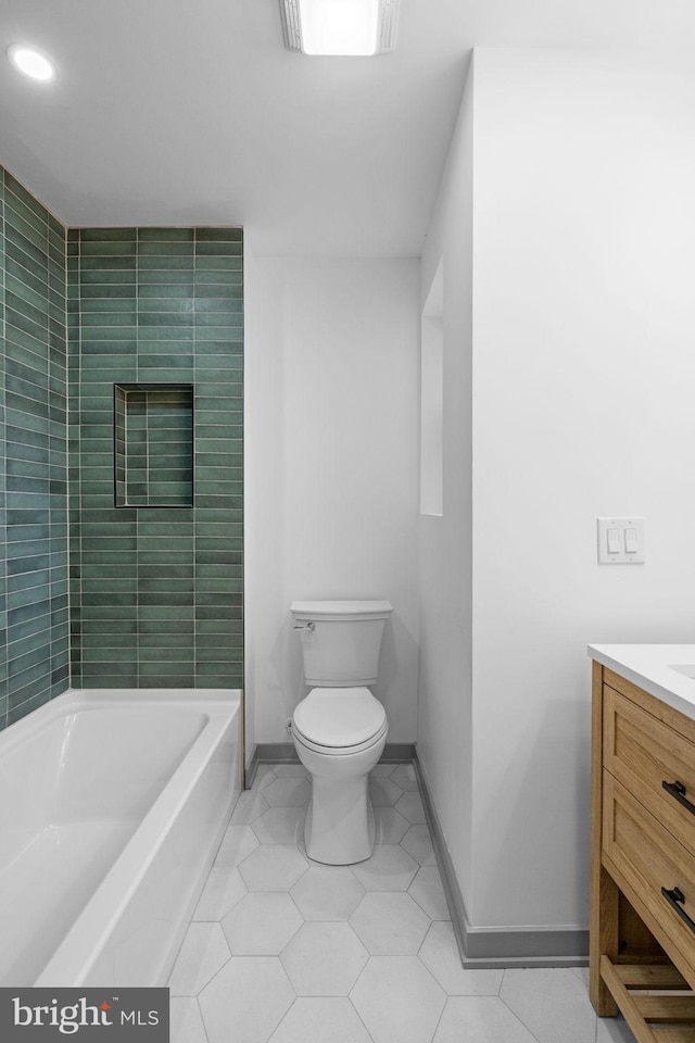 bathroom with tile patterned flooring, a bath, vanity, and toilet