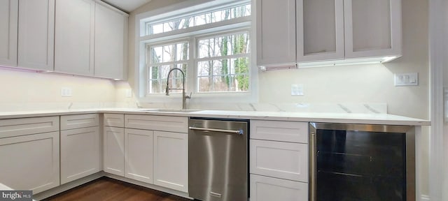 kitchen with light stone countertops, stainless steel dishwasher, beverage cooler, sink, and white cabinets