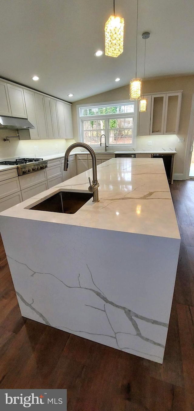 kitchen with sink, stainless steel gas cooktop, an island with sink, vaulted ceiling, and decorative light fixtures