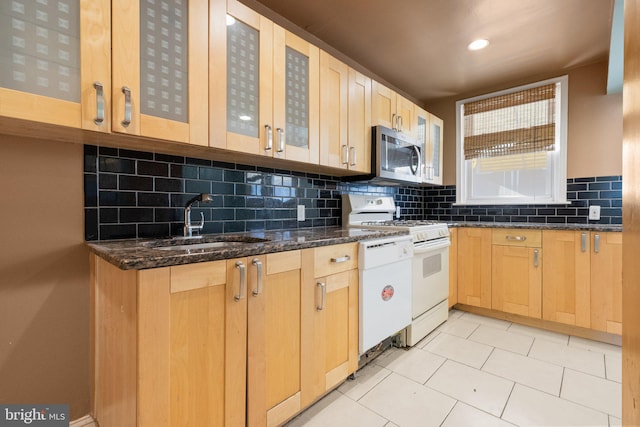 kitchen with white appliances, backsplash, dark stone counters, sink, and light brown cabinetry