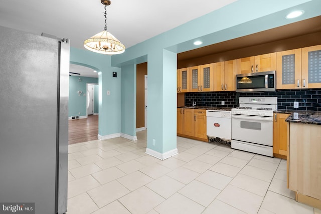 kitchen with decorative backsplash, white appliances, pendant lighting, light tile patterned floors, and dark stone countertops