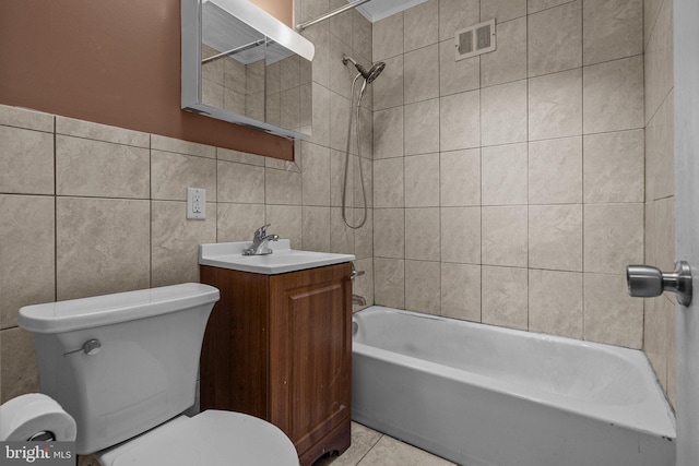 full bathroom with vanity, tile patterned floors, tiled shower / bath combo, toilet, and tile walls