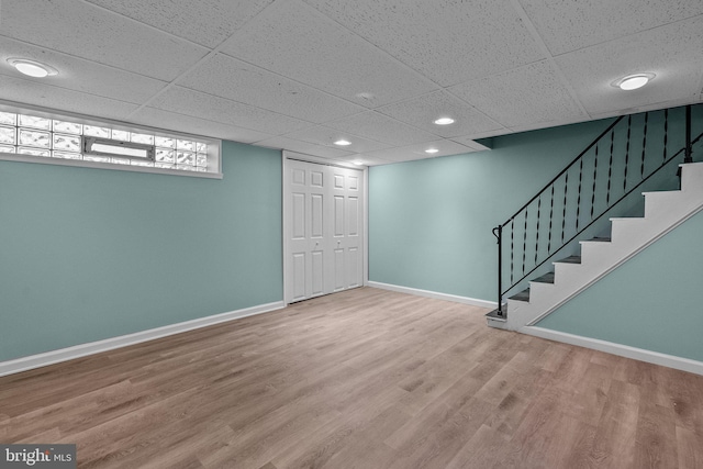 basement featuring a paneled ceiling and wood-type flooring