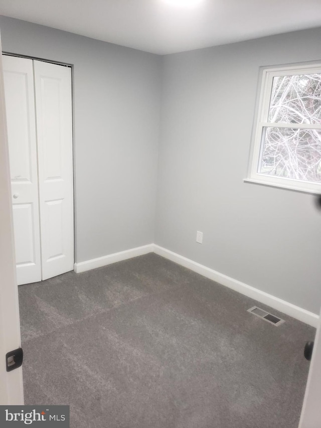 unfurnished bedroom with a closet and dark carpet