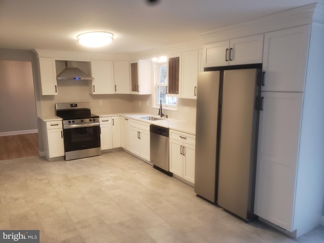 kitchen featuring white cabinets, wall chimney range hood, sink, and appliances with stainless steel finishes