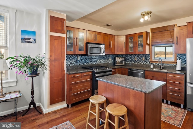 kitchen featuring stainless steel appliances, a healthy amount of sunlight, sink, a center island, and dark hardwood / wood-style floors