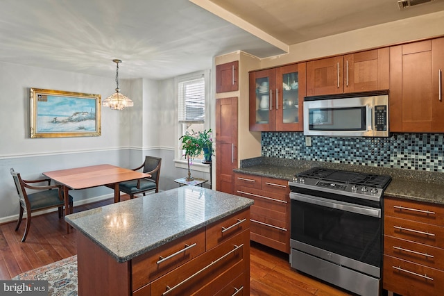 kitchen with dark hardwood / wood-style floors, appliances with stainless steel finishes, and tasteful backsplash