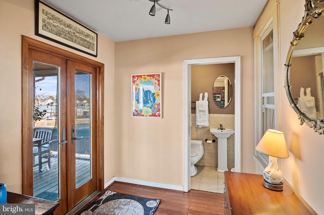 entryway with sink, french doors, tile walls, and light hardwood / wood-style flooring