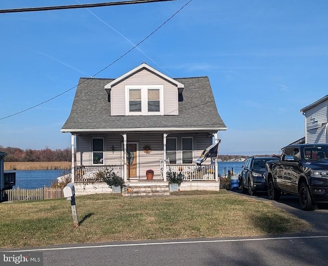 view of front of home with a front lawn, a water view, and covered porch