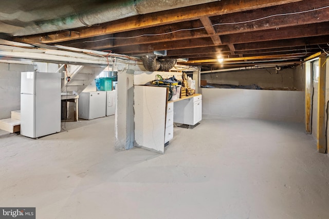 basement with washer and clothes dryer and white refrigerator