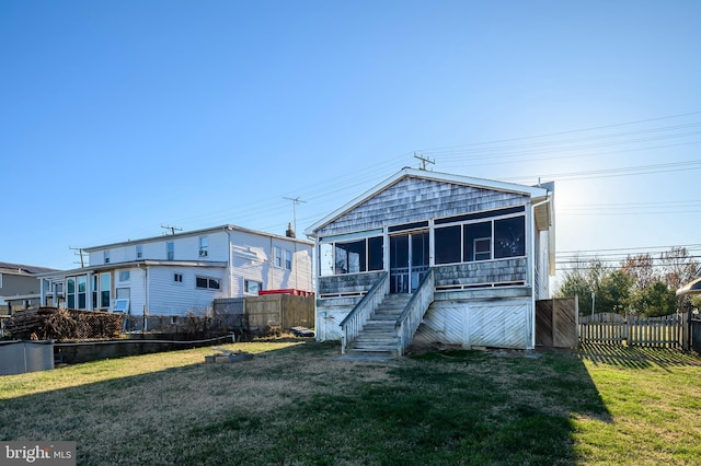 rear view of property with a sunroom and a lawn