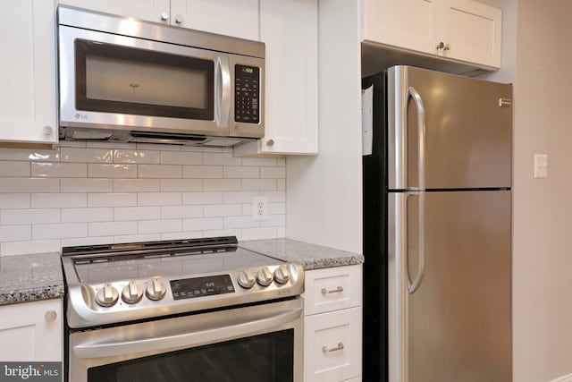 kitchen featuring stainless steel appliances, decorative backsplash, white cabinets, and light stone counters