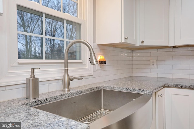 details with white cabinets, tasteful backsplash, and sink