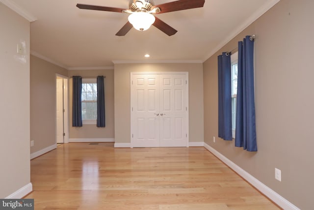 unfurnished bedroom with ceiling fan, a closet, light wood-type flooring, and crown molding